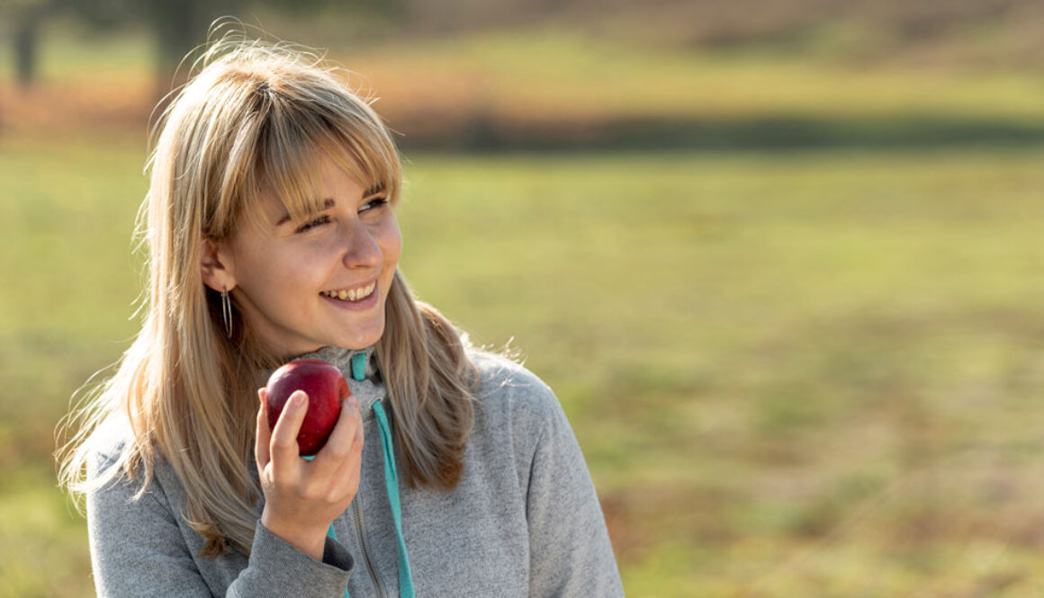 smiling-blonde-woman-eating-delicious-apple