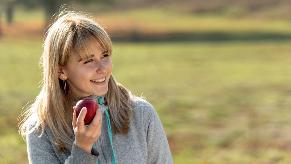 smiling-blonde-woman-eating-delicious-apple