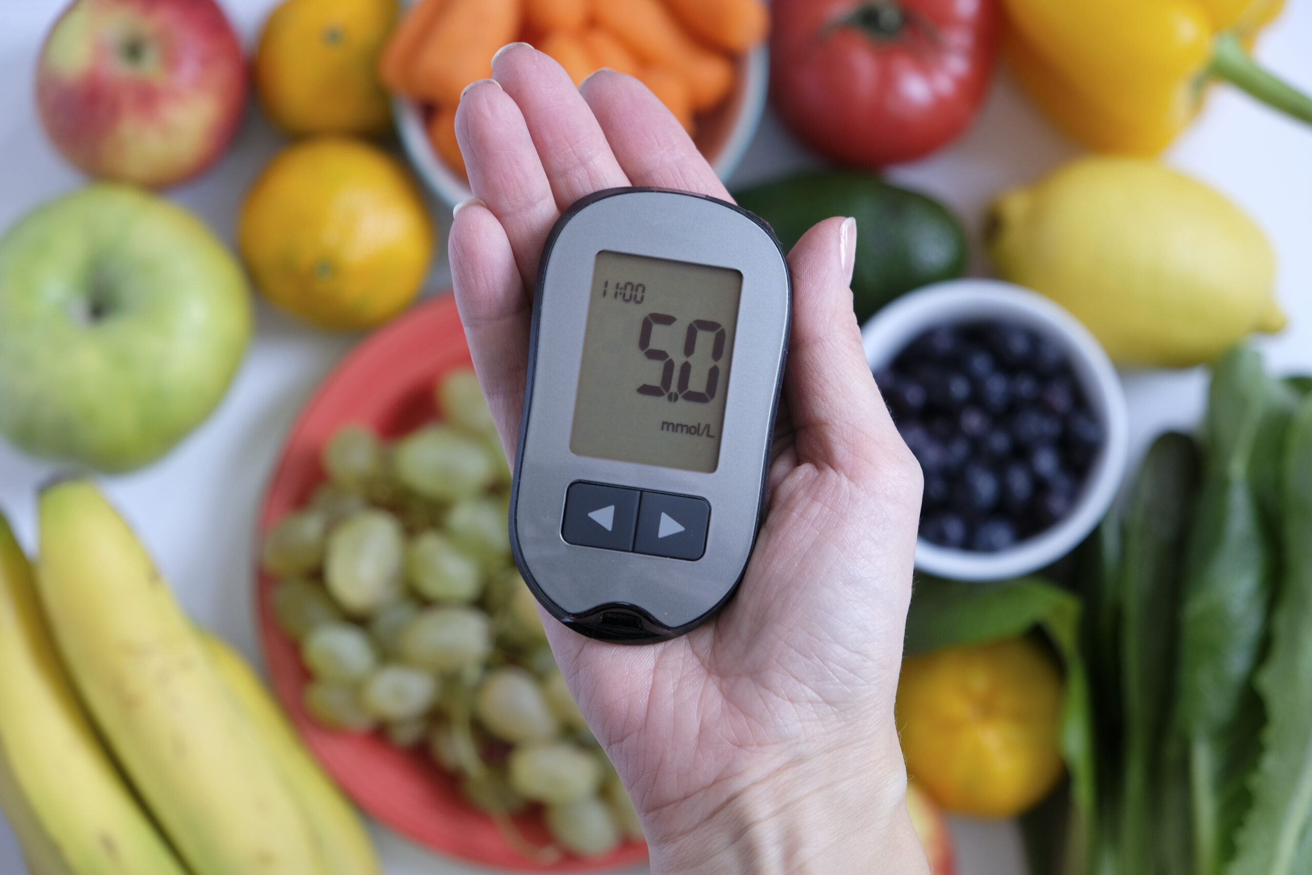 Diabetes concept: glucometer in hand and healthy food. Nutrition cause diabetic desease