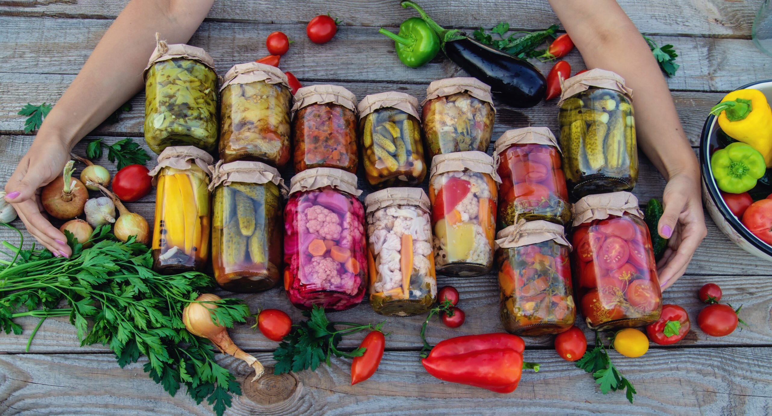 Woman canning vegetables in jars on the background of nature. preparations for the winter